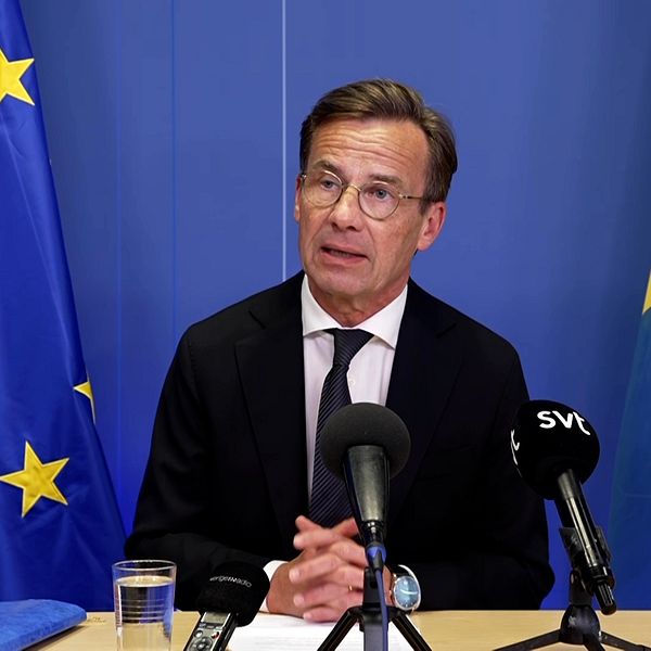 Ulf Kristersson talar vid presskonferens med EU- och Sverige-flaggor bakom sig