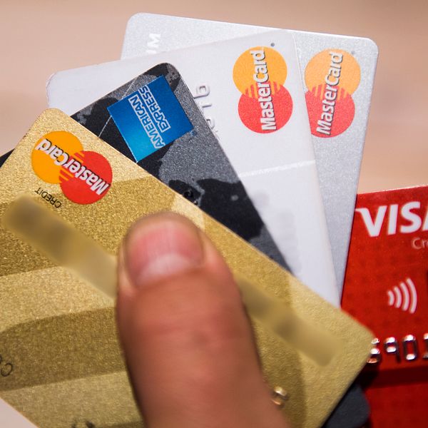En hand håller flera kreditkort från Mastercard och Visa.