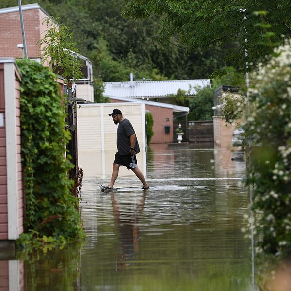 Man som går genom vatten i ett bostadsområde