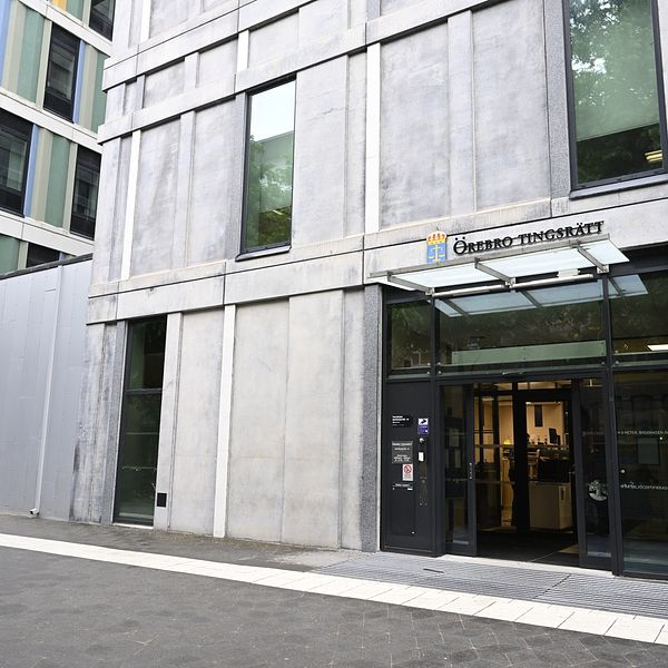 Entrén till en modern byggnad som tillhör ”Chalmers Tekniska Högskola”. Fasaden är i betong med stora fönster och ett klart överhäng vid ingången, som är markerad med en glasdörr. Byggnaden ligger i ett område med flera moderna byggnader i olika färger.
