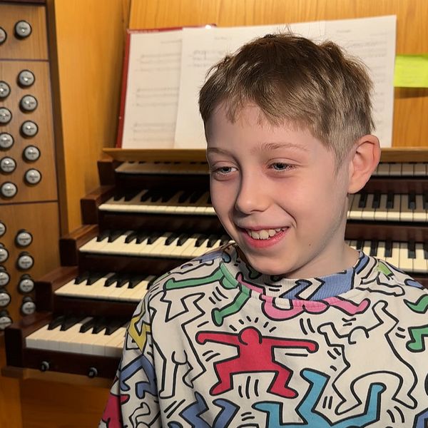 Person framför orgel med färgstarkt mönstrad tröja.