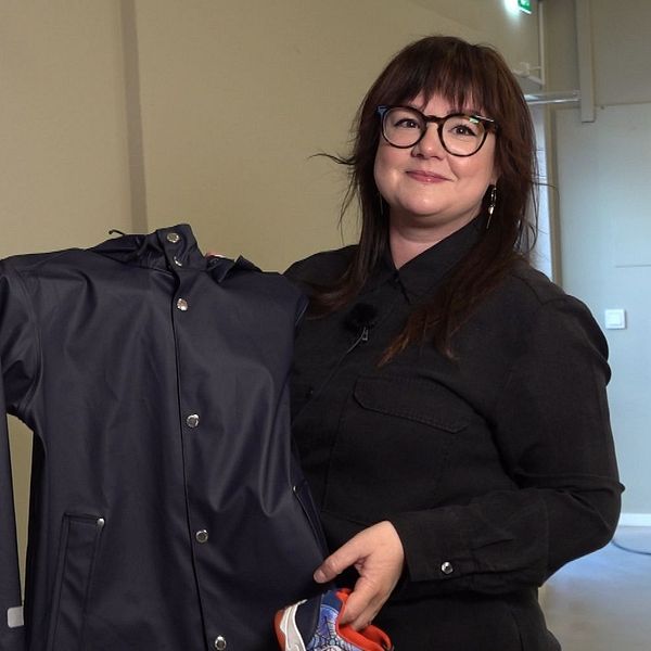 Butikschefen Kajsa Johansson håller upp ett par skor och en regnjacka i den nya klädbutiken Klädrätt, i Rannebergen, som är en butik där ekonomiskt utsatta får tillgång att handla nya kläder för ett billigt pris.