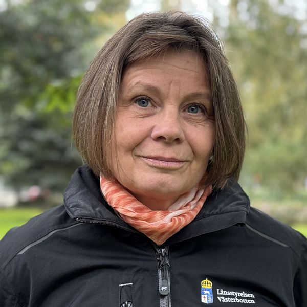 Kajsa Berggren, länsstyrelsen Västerbotten står framför en park med gröna träd och buskar i bakgrunden. I det övre vänstra hörnet syns en röd fyrsiffrig räknare med numret ”321”.