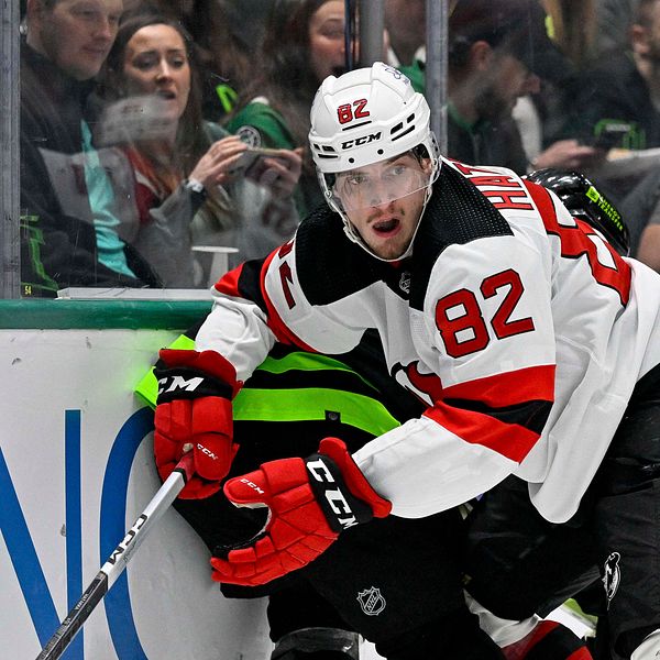 Ishockeyspelare från New Jersey Devils strider om pucken intill sargen under match.