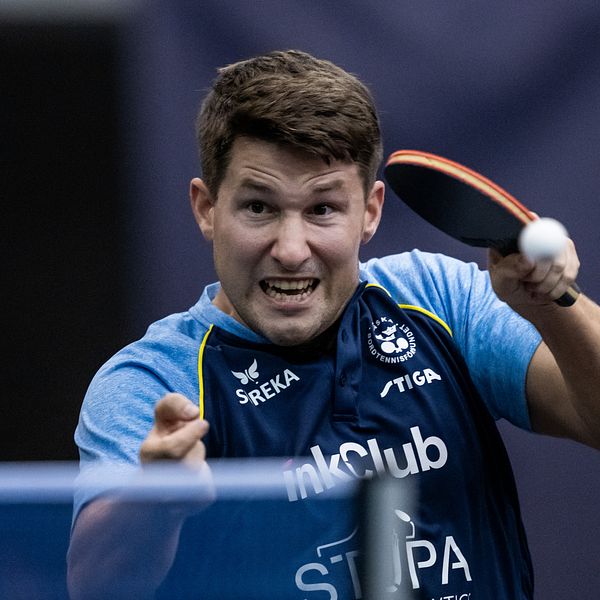 En bordtennisspelare slår en boll med ett racket.