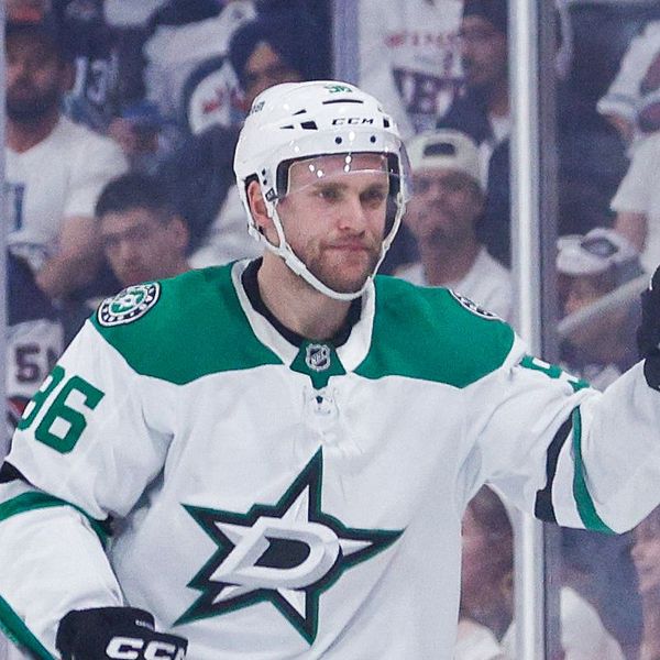 Ishockeyspelare i Dallas Stars firar mål mot motståndarlag, domare syns till vänster.