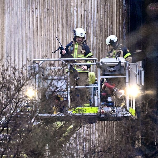 Brandmännen med gevär i korgen på höjdfordonet.