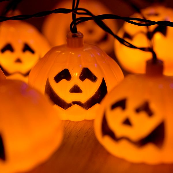 Ljusdekorationer i form av små, plastepumpor med ansikten, som lyser i orange och skapar en festlig atmosfär inför Halloween.