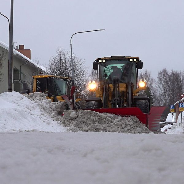 En hjullastare plogar en gata med grådassig snö.