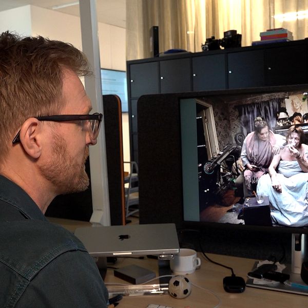 Person sitter vid skrivbord och tittar på bilder på en datorskärm.