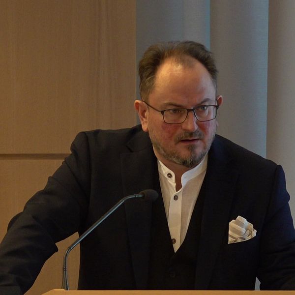 Person med kostym i en talarstol.