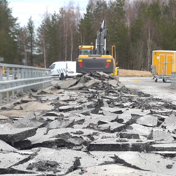 Uppriven asfalt med grävmaskin i bakgrunden