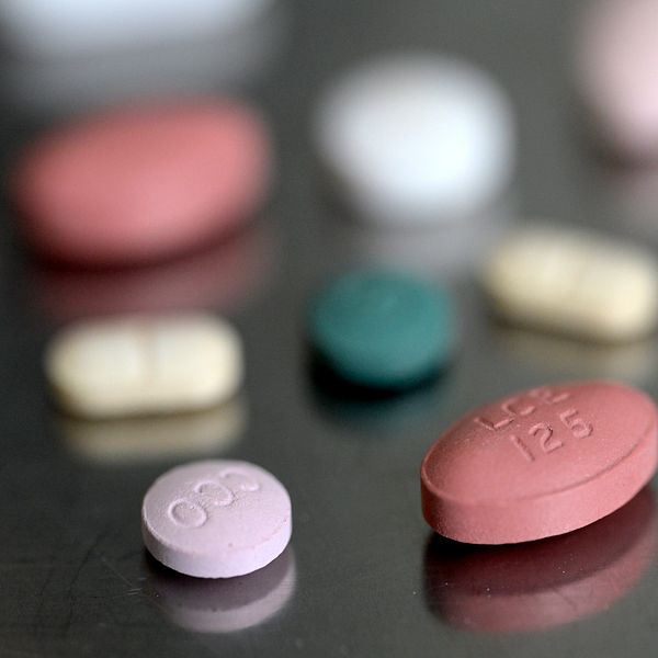 Olika typer av färgglada piller spridda på en yta, inklusive oidentifierade röda, rosa, vita och gröna tabletter.