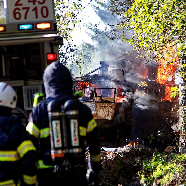 räddningstjänst släcker en båt som står på land och brinner