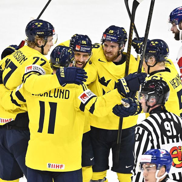 Svenska ishockeyspelare i gula tröjor firar mål mot ett lag i blå och röd utrustning.