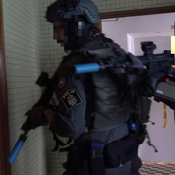 Flera poliser går in i en byggnad klädda i skyddsutrustning och utrustade med automatvapen