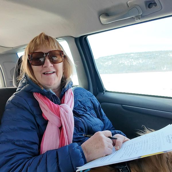 Kvinna sitter i bil under en gratisskjuts i Tavelsjö. Hon skriver på en blankett.