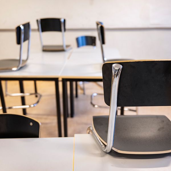 Stolar upp-och-ned på bord i ett klassrum.