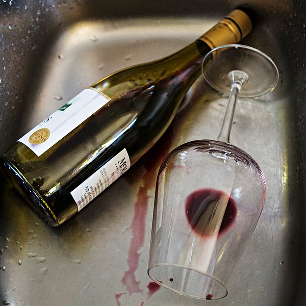 Vinflaska och vinglas med vinslatt ligger i diskho.