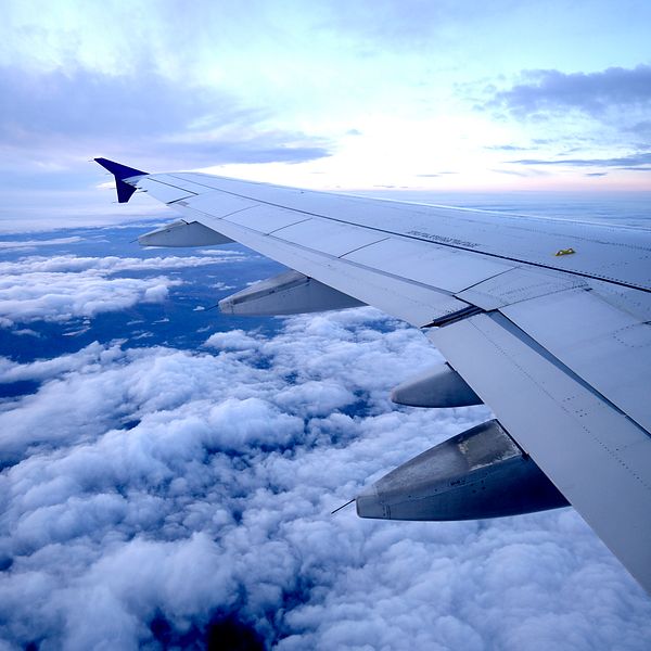Bild tagen inifrån ett sas-flyg uppe i luften. Vänstravingen av flygplanet uppe i himlen med moln.