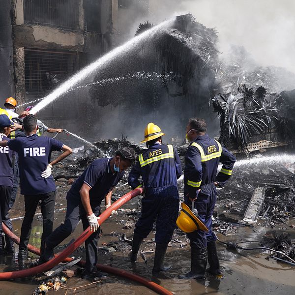 Brandmän släcker eld bland rasmassor efter en brand eller explosion.