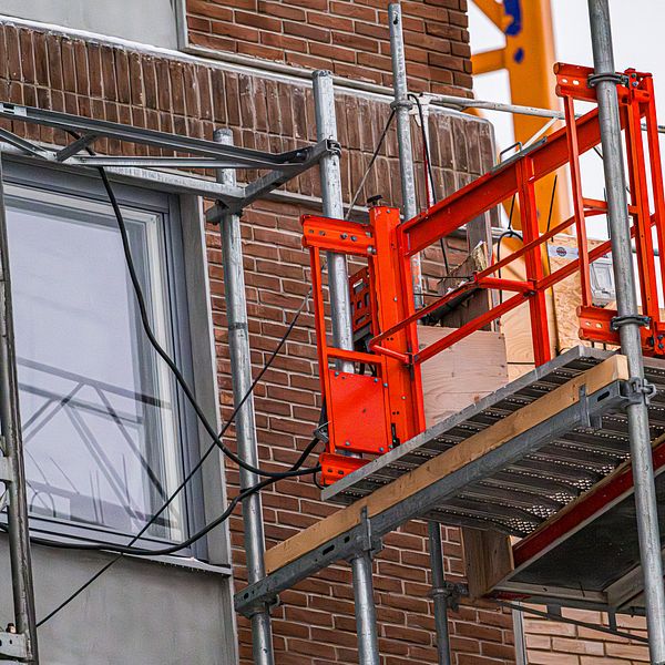 En orange arbetshiss på ett husbygge