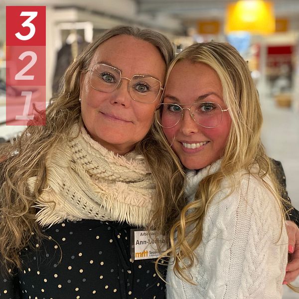 Två personer omfamnade i en butik med kläder i bakgrunden.