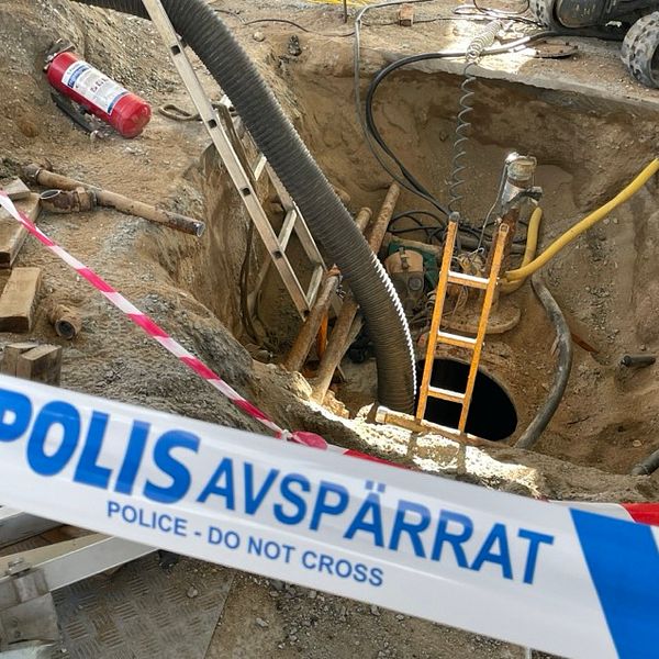 Avspärrat bygge med polistejp runt ett hål i marken och en stege som leder ner.