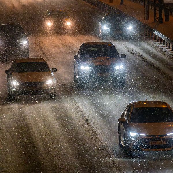 Bilar på motorväg i snöig väderlek.
