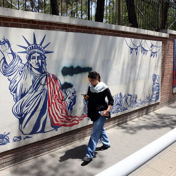 Person går förbi en muralmålning av Frihetsgudinnan med iransk flagga i Iran