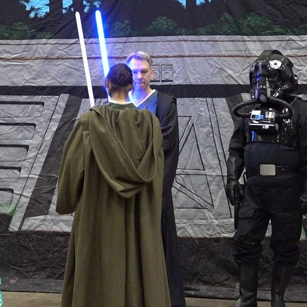 Fem personer i Star Wars-kostymer poserar framför en rymdtema bakgrund.