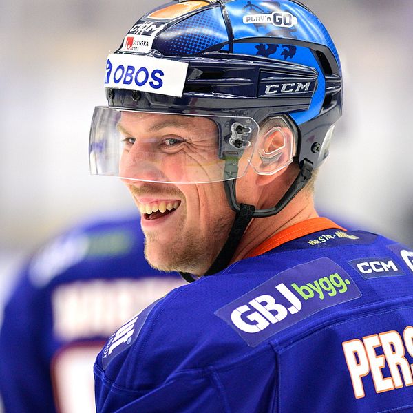 Närbild på ishockeyspelare Joel Persson som ler. Har hjälmen på och är på isen.