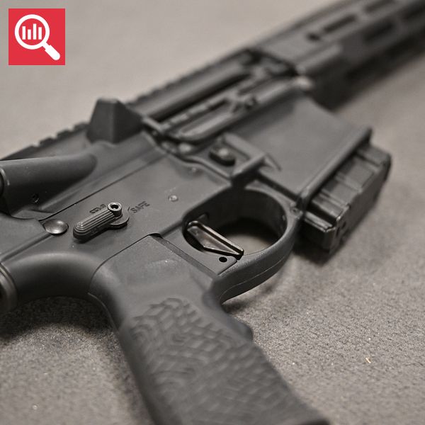 Ett närbildsfoto av en AR-15-stormgevär, fokuserat på avtryckaren och delar av pistolgreppet, med en suddig bakgrund.