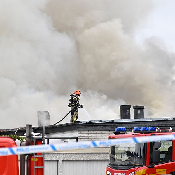 Brandman på taket och rök, brandbil framför hus