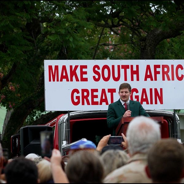 Man talar inför folkmassa vid skylt med texten ”Make South Africa Great Again”.