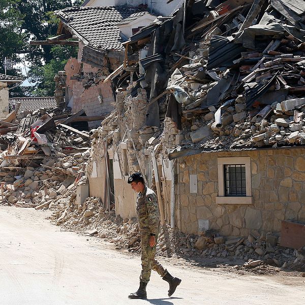 En italiensk soldat går förbi hus som står i ruiner i Villa San Lorenzo, nära byn Amatrice.