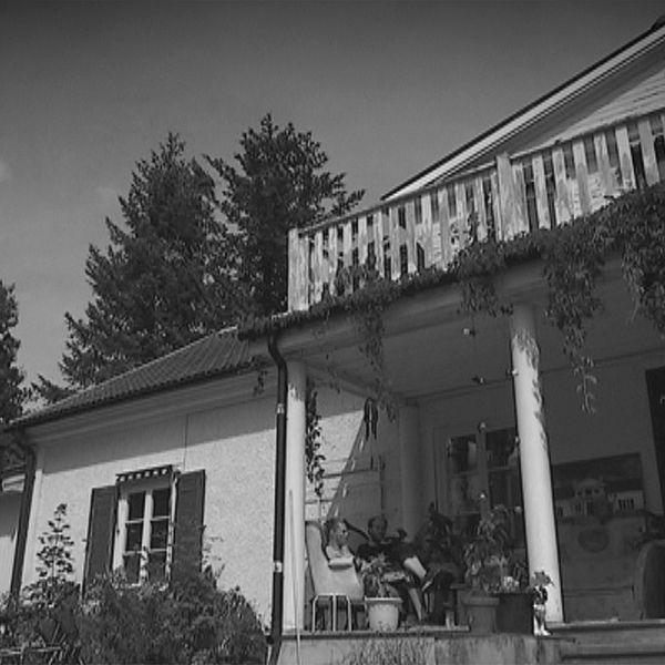 Ett vitt hus, vildvin växer på pelare på farstubron.