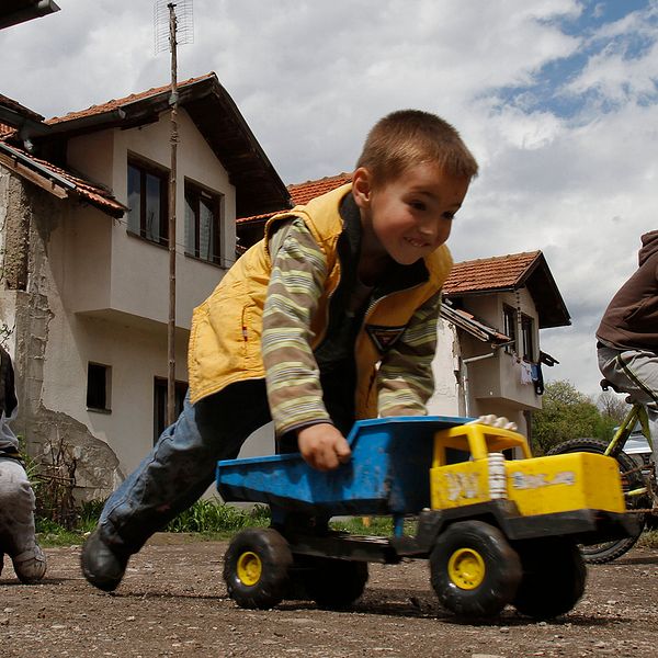 Tre barn leker med lastbilar och en cykel i norra Bosnien.