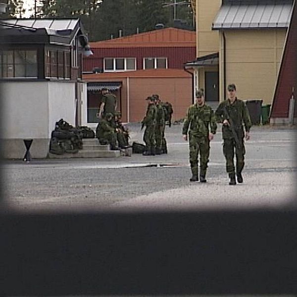 Två militärer går mot grind i förgrunden