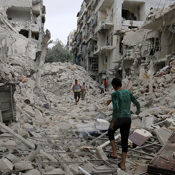 Människor går omkring i ruinerna efter bombningar i Aleppo på fredag.