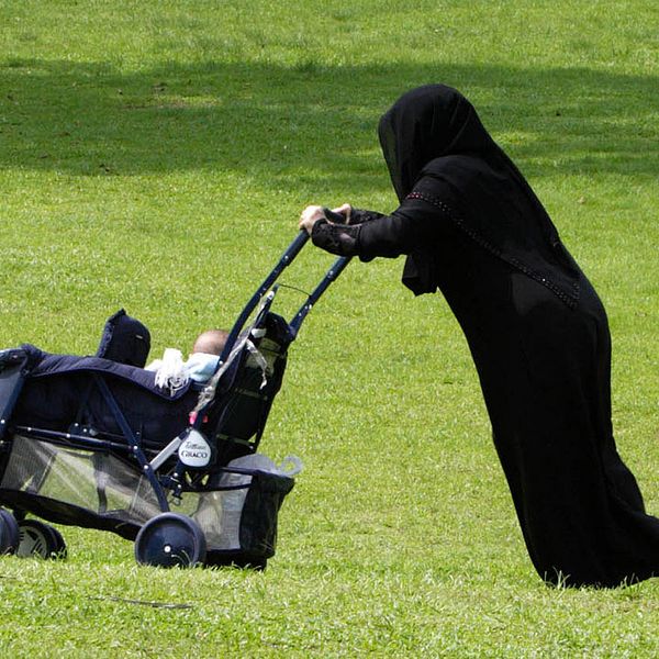 En kvinna med burka och barnvagn