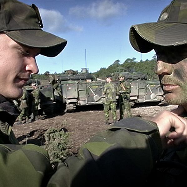 Soldater fixar krigsmask inför övning på Tofta skjutfält.