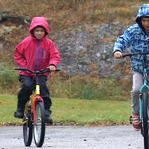 Två barn cyklar ute på gatan.
