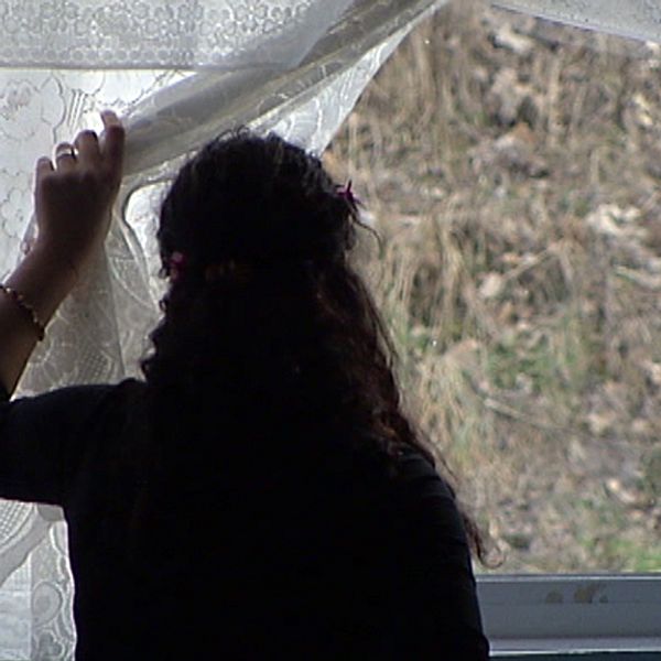anonym kvinna tittar ut genom fönster