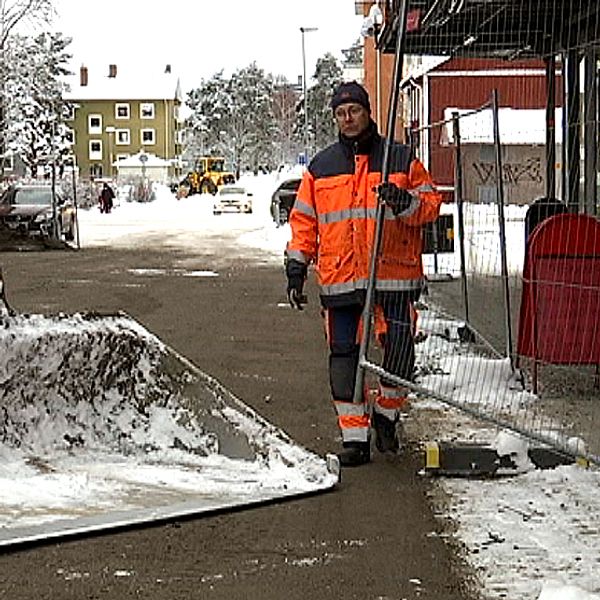 Två arbetare i varselkläder plockar bort staket.