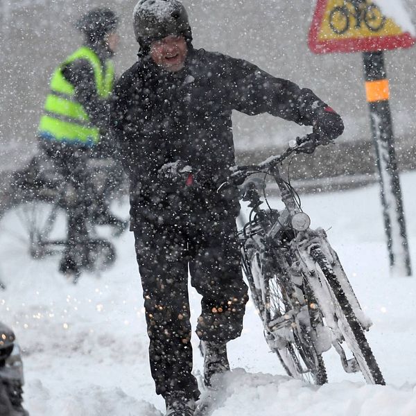 Cyklist leder cykel i snöoväder