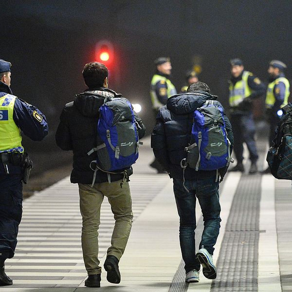Polis eskorterar asylsökande efter genomförd gränskontroll.