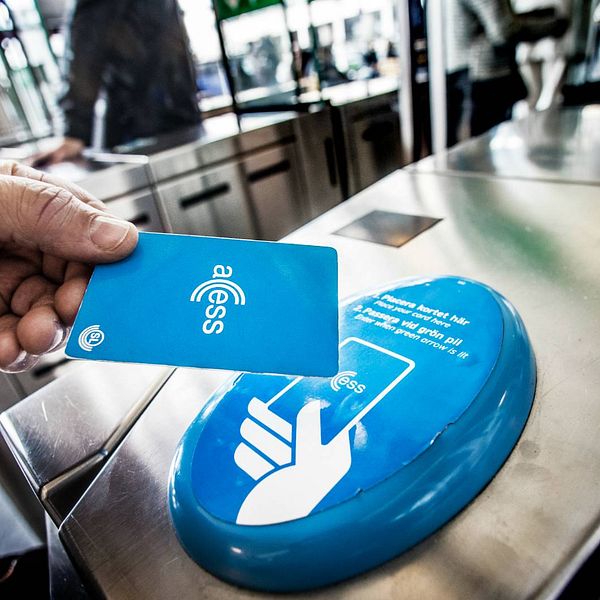 en hand håller ett access-kort över en kortläsare i t-banan