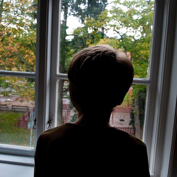 Ensam pojke vid ett fönster.