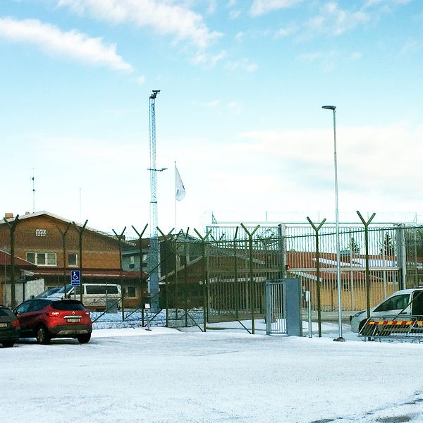 parkerade bilar på snöig plan utanför fängelsets stängsel